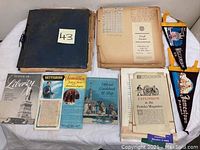 Photo of the vintage dark blue scrapbook, loose pages with typed notes, brochures including Statue of Liberty, Gettysburg, Jamestown, and pamphlets
