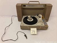 Full view of the General Electric portable stereo record player with handle, power cord, and speakers visible.