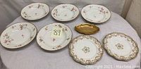 Photo showing 3 bowls, 3 salad plates, 1 oval gold candy dish, 2 ornate floral plates with gold trim