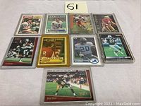 Photo showing 9 NFL trading cards from 1980s-90s including Joe Montana, Dan Marino, Steve Young, Deion Sanders, Joe Greene, Barry Sanders, Andre Rison.