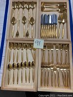 Full view of the organized flatware set displayed in wooden trays showing all forks, knives, spoons including salad servers.