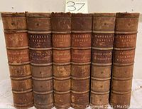 Photo of six antique leather bound volumes of Sir Walter Scott Waverley Novels showing spine titles and wear.