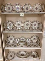 Full shelf display of the china set showing multiple plates, serving bowls, and a covered casserole dish.