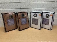 Four curtain packages: Two brown patterned curtian pairs and two white curtain pairs, each in protective zippered plastic bags, with brand labels and grommets visible.