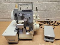 Front view of off-white JC Penney serger sewing machine with adjustment dials and spool holders.