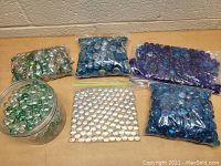 Overview of assortment of glass marbles in plastic bags and jar placed on table