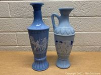 Photo showing two blue Greek style ceramic decanters with classical motifs and figures in white detail.