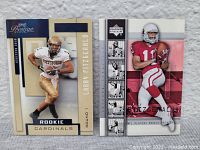 Two rookie cards of Larry Fitzgerald pictured side by side against a gray background wall. One card features Fitzgerald in a white Pittsburgh uniform, the other in a red Arizona Cardinals uniform.