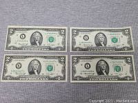 Four 1976 U.S. two dollar bills laid flat, showing front side with Thomas Jefferson portrait.