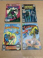 Four vintage DC Comics comic books arranged on a wooden surface showing front covers: Scary Tales, Unknown Soldier, Super Friends, and Superman.