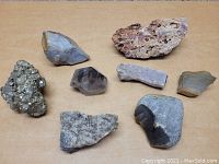 Lot of eight assorted rocks and geodes arranged on a wooden surface showing variety and textures