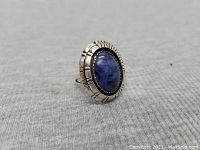 Side angled photo showing the blue oval stone and detailed sterling silver setting with a split band.
