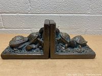 Pair of turtle-themed metallic bookends side by side, showing their matching design with detailed turtle figures and textured rocky bases.