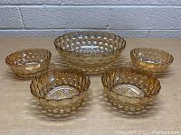 Front view of 5-piece set of vintage amber glass bowls with bubble texture; one large bowl and four smaller matching bowls.