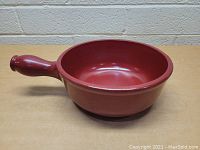 Side view of Emile Henry stoneware warming pot showing handle and round shape.
