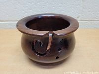 Front view of round Sheesham wood yarn bowl with swirl motif cut into the rim and smooth finish.