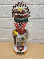 Front view of the vintage Ezra Brooks Kachina whiskey decanter bottle with detailed colorful ceramic design and label on the base.