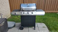 Front view of the Char-Broil Classic propane BBQ grill showing the lid, main burners, and side burner with stainless steel shelves on each side.