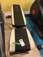 Full length view of Marcy weight bench, showing black and white color scheme and padded surfaces.