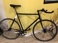 Side view of black Fuji Classic steel road bicycle with drop handlebars, saddle, chainring and wheels