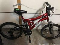 Side view of the red Revolution Reactor bike showing frame, wheels, and seat.