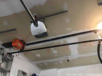 Garage Gator hoist system mounted on garage ceiling showing rail, motor and hooks