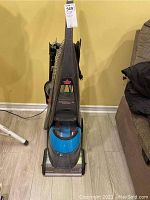 Front view of one Bissell DeepClean ProHeat 2X Professional Pet carpet cleaner showing upright black and blue plastic body and attached hose.