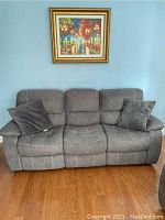 Front view of grey-brown suede three-seat sofa with two throw cushions