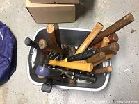Top-down view of bin filled with assorted hammers of different handles and heads.