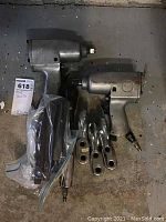 Full lot view showing two pneumatic impact drills, one impact wrench, four metal hooks, and a plastic bag with parts.