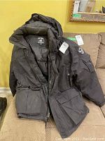 Front and hood view of the men's down coat showing brand label and exterior pockets.