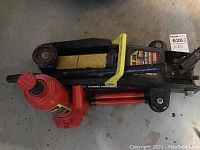 Photo showing two hydraulic jacks stacked, highlighting black floor jack and red bottle jack