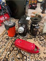 Four kitchen appliances shown: Philips juicer (black), Simbr air popcorn popper (red), electric coffee grinder (black), red 5 minute chef appliance.