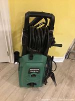 Full view of the green and black Certified 1800 PSI electric pressure washer with hose wrapped over top handle.