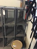 Two gray plastic shelving units side by side, showing full height and shelf levels with some storage visible.