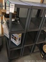 Photo showing 2 dark grey plastic shelving units with four shelves each, sized approximately 23x11x48 inches.