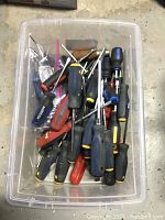 Top view of plastic bin filled with assorted screwdrivers of various makes and sizes
