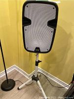 Front view of QFX Bluetooth party speaker with white perforated grille and black frame on an adjustable tripod stand.