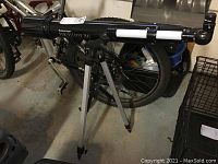 Side view of Celestron PowerSeeker 70AZ telescope showing black tube, tripod, and background bicycle.