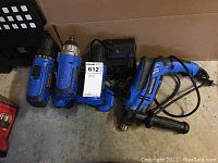 All four tools shown: three blue cordless drills and one corded blue and black hammer drill.