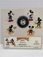 Front view of the display board with the coin in capsule and colorful Mickey Mouse illustrations, includes details about limited edition and mint info.
