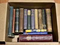 Eleven hardcover books arranged inside a cardboard box, spines show titles on literature, history, music from the 19th and 20th centuries.