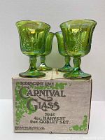Four iridescent lime carnival glass goblets displayed on and around the original box labeled with brand and product details.