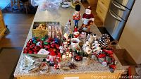 Wide view of all Christmas decoration items on kitchen counter including nutcracker, snowman, ornaments, candles, and other decorations