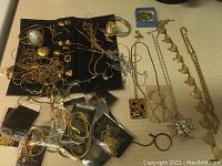 Full overview of assorted costume jewelry including necklaces, bracelets, pins, and earrings, arranged on black cloth.