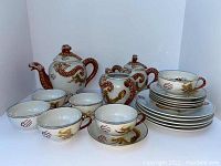 Full view of tea set including teapot, sugar pot, creamer, six teacups, six saucers, and six luncheon plates arranged in display.