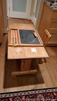 Full view of the wooden kids table showing the chalkboard, abacus, and chalk tray on one side, with the chair placed behind it on wood flooring.
