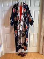 Black floral kimono hanging on door with red lining showing.