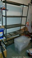 Full view of metal shelving unit showing five shelves with signs of scratches and rust spots.
