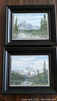 Two framed landscape paintings one above the other, showing full view of lot